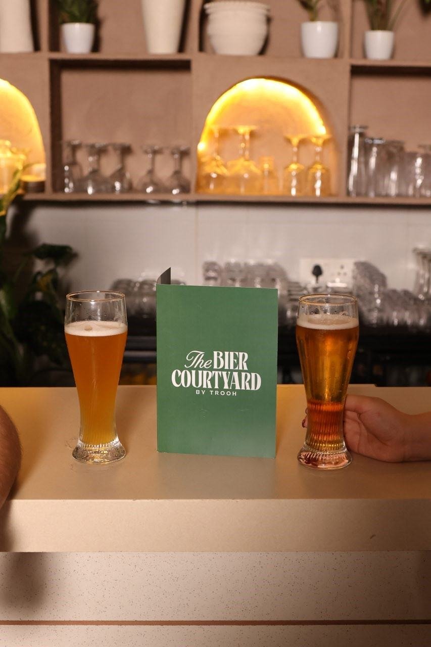 Two glasses of craft beer beside the TBC menu at the bar, one of the best bars in Pune
