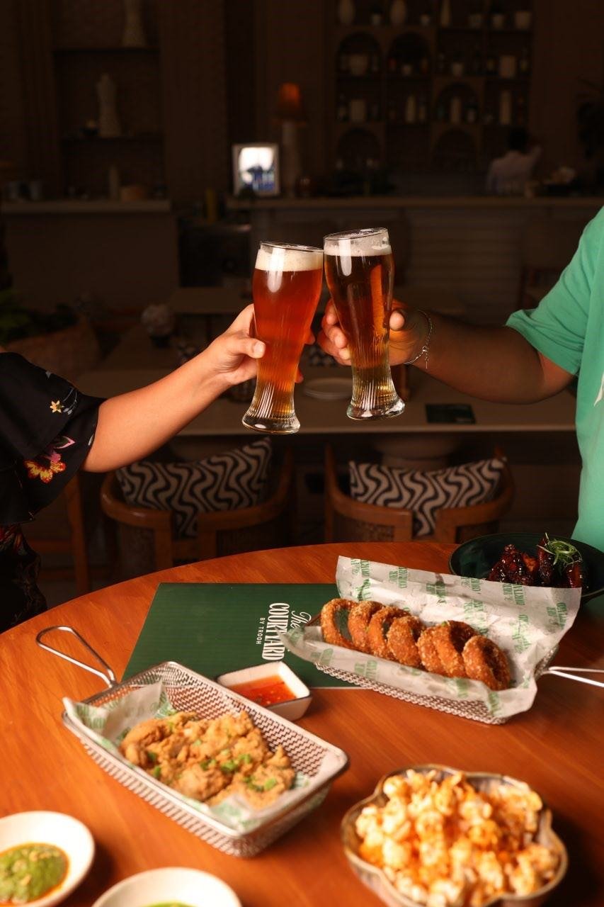 Friends toasting at a courtyard table at TBC, one of the best nightlife spots in Pune